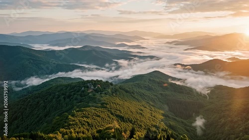 Majestic sunrise illuminates rolling green mountain landscape with thick clouds blanketing serene valleys below at dawn.