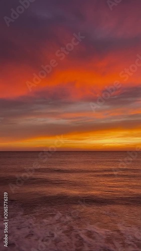 Vibrant sunset over calm ocean waves with dramatic clouds, slow motion, representing peace, tranquility, and breathtaking natural beauty