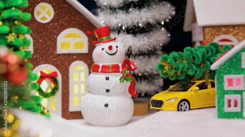 Near the big Christmas tree in Christmas town, in front of the colorful houses, there are snowmen with letters and Santa Claus with a gnome