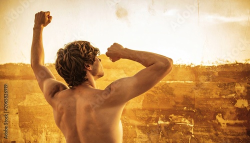 Man celebrates outdoors with arms raised warm sunlight and scenic backdrop