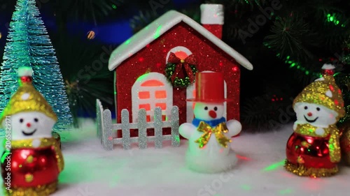 Near the red house there are three snowmen with Christmas trees and a yellow ball