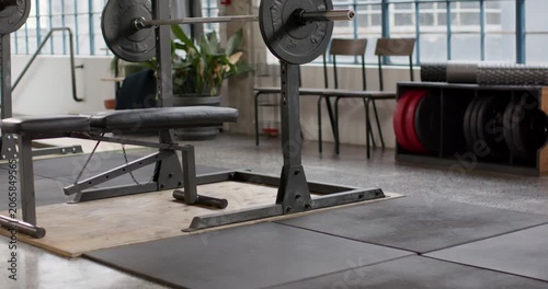 Camera is pulling back and tilting up from low view, revealing loaded barbell and bench centered