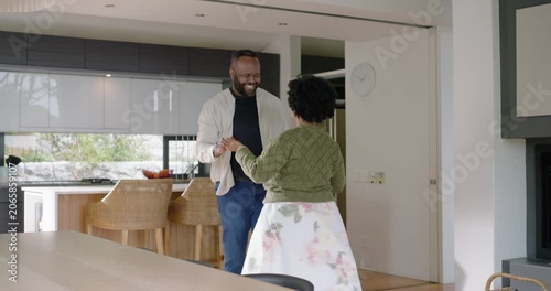 African couple clasping hands, twirling, swaying and embracing, showing love in kitchen near island