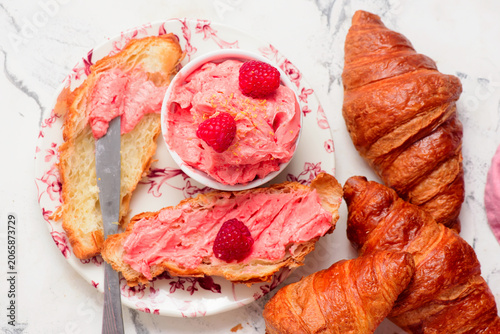 Raspberry butter spread on fresh croissants