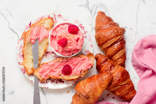 Raspberry butter spread on fresh croissants