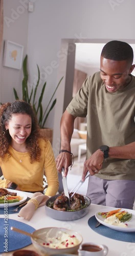 Vertical video: Couple watching man placing fork, carving roast with knife at home preparing meal