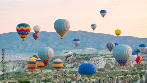 Many colorful hot air balloons over Cappadocia rock valley at sunset