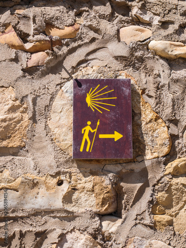 Pilgrimage trail marker on stone wall with scallop shell symbol