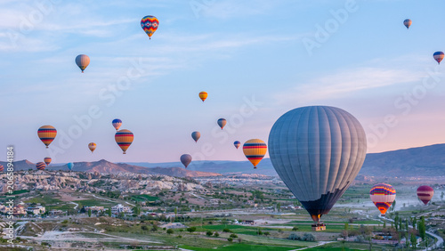 Hot air balloons flying over Cappadocia valley with mountains at sunrise