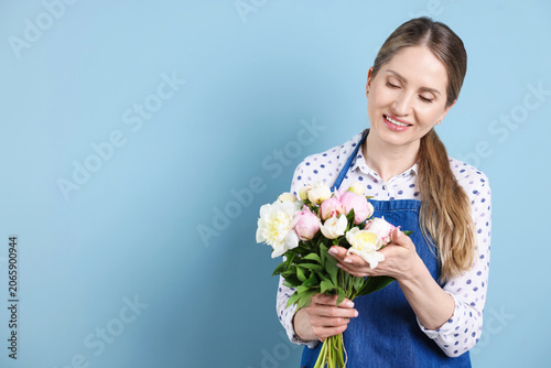 Florist with bouquet of beautiful peonies on light blue background. Space for...