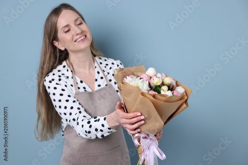 Florist with bouquet of beautiful peonies on light blue background. Space for...