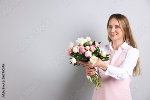 Florist with beautiful peonies on light background. Space for text