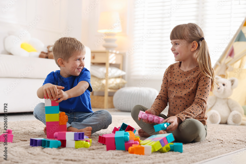 Obraz premium Little kids playing with colorful blocks on floor at home