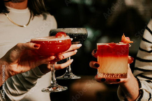 Multi-generational women clinking colorful elegant cocktails at a high-end social event