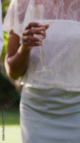 Vertical video: Holding woman steadying flute after first touch to set low at garden in lace top