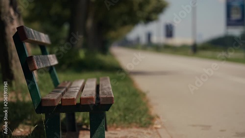 Wooden bench beside a pedestrian and cycling path at Jarun Zagreb Croatia with shallow depth of field and blurred background.