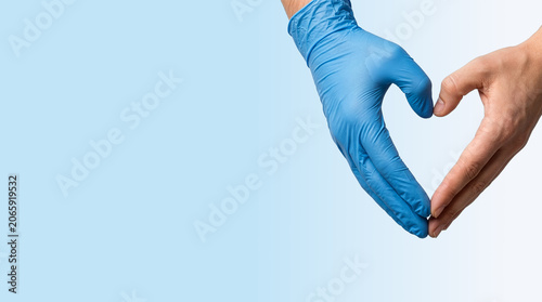 Bare hand and blue gloved hand forming a heart shape on blue background