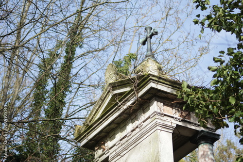 Slika na platnu Overgrown historic mausoleum rooftop with cross and angel sculpture in old Frenc