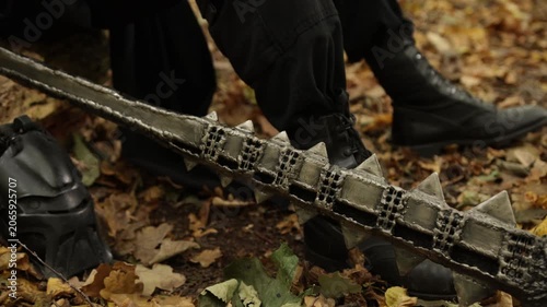 Forest floor, Forest flail, Weapon ground. On forest floor, spiked metal weapon is positioned among fallen leaves, with boots appearing in background.