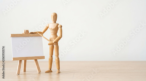 Mid-year performance reviews and KPI tracking concept with a wooden mannequin giving a presentation on a blank easel whiteboard with copy space for business growth analysis banner
