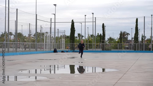 Young Boy Running Across Sports Court After Rain Outdoors