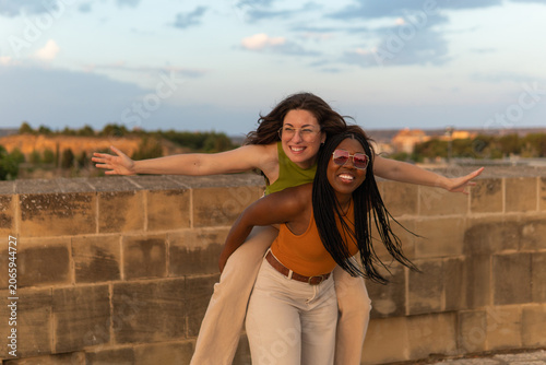 Картината върху платно Happy young women enjoying piggyback ride outdoors