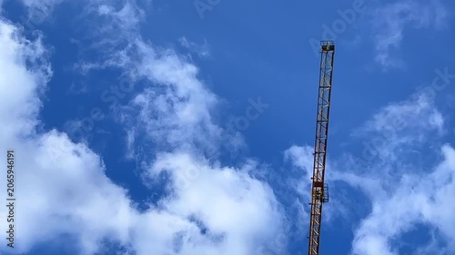Tower crane on the construction site against sky with clouds