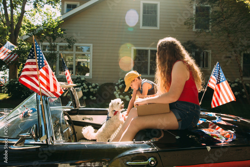girl and boy sitting in car with american flag
