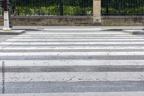 Canvas Print Crosswalk with worn paint in urban area near trees and buildings during daylight