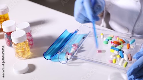 Pharmacist sorting different pills at white table in clinic, closeup