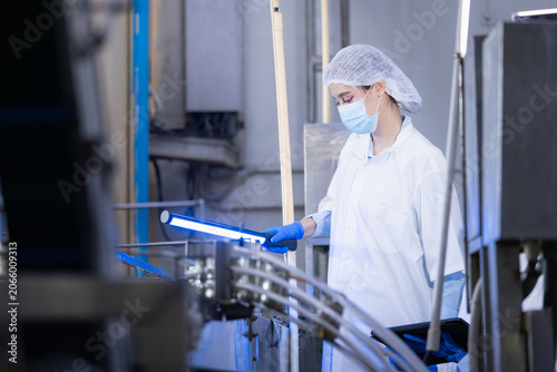 Obraz na plátně Female quality control workers using UV light to inspect production line in food