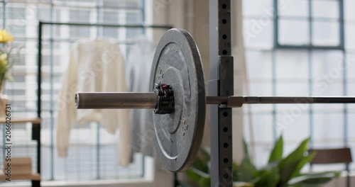 Dolly movement is pushing camera to pan and pull back, revealing loaded barbell end near windows