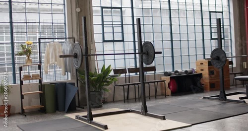 Camera is panning while squat rack with loaded barbell is staying centered, revealing gym layout