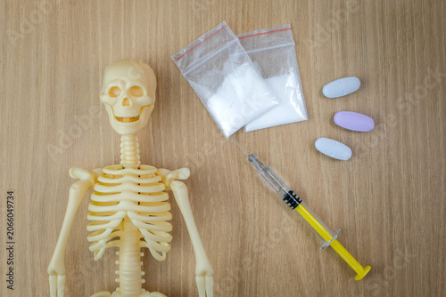 Canvastavla A skeleton anatomy model, syringe, tablets, and a small white powder bag are placed on a wooden table