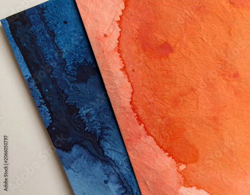 Textured orange and indigo blue watercolor paper background with ink bleeding