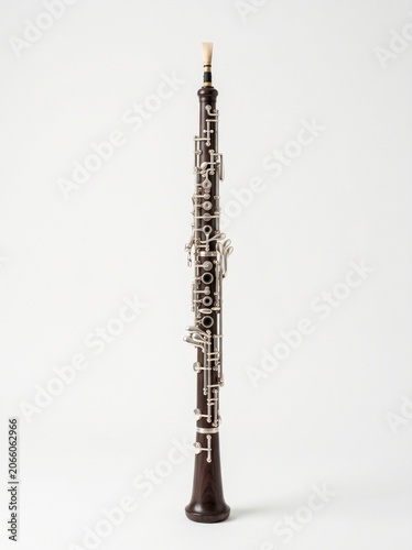 A professional dark wood oboe with silver keys and a reed on a clean white background