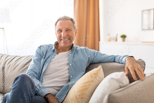 Cuadro en lienzo Smiling Elderly Caucasian Man Relaxing On Cozy Sofa At Home, Enjoying Peaceful Moment, Exuding Happiness And Contentment In Comfortable Living Room Setting, Lifestyle Concept