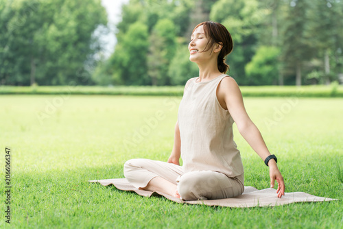 Bild auf Leinwand Asian women taking deep breaths, stretching, and doing yoga in a park