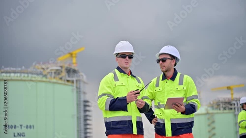 Male Petrochemical Worker Team Use Tablet And Radio For Facility Inspection