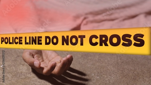 Crime scene concept with a dead body lying on the ground covered by a cloth, behind a yellow tape with the text POLICE LINE DO NOT CROSS.
