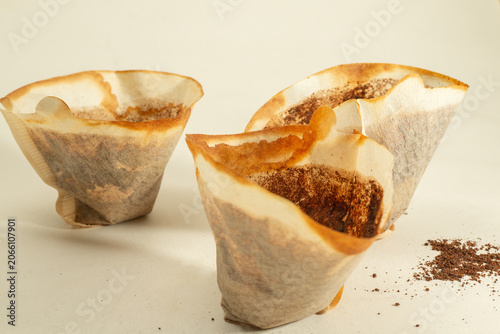 Drip black coffee with coffee filter and coffee grounds on a white background.