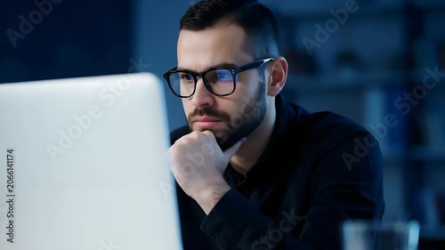 Businessman working late at night on computer in office thinking deeply about project deadline