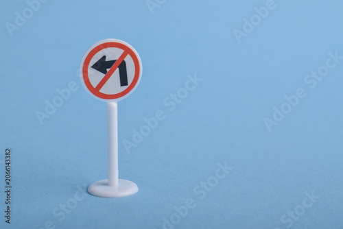 Obraz na plátně Miniature no left turn traffic sign isolated on blue background, representing traffic regulations, prohibited directions, road safety, and transportation concepts