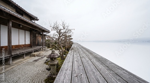 Surrealism. Japanese engawa veranda extending infinitely into open winter sky beyond the garden, impossible wooden horizon, concept of infinite space