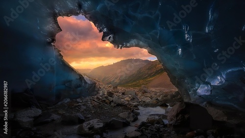 View of mountains and sunset through a rocky cave opening