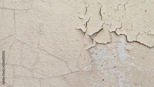 Obraz na plátně A wall with cracked and peeling paint because it's old and exposed to heat and rain, the wall paint is cream-colored