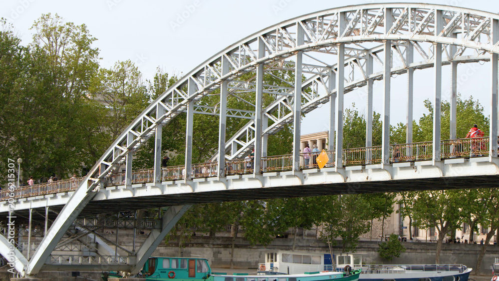 Fototapeta premium Pedestrians Crossing the Steel Arch Debilly Footbridge Over the Seine River