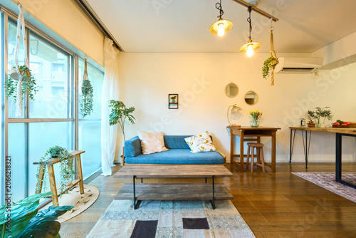 Living room with blue sofa and many potted plants near window
