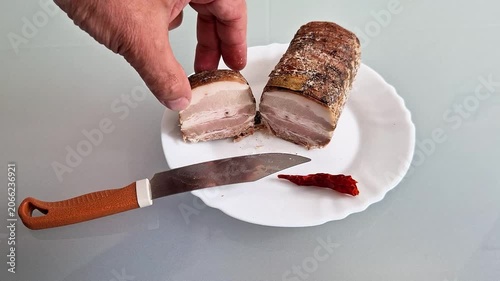 Rustic smoked pork belly slices served on a plate with a carving knife, showcasing traditional cured meat, rich smoky texture, appetizing presentation, and homemade culinary craftsmanship