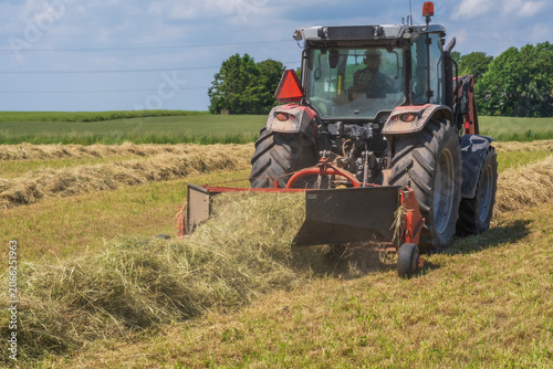 Εκτύπωση καμβά Red tractor raking hay on a sunny summer field